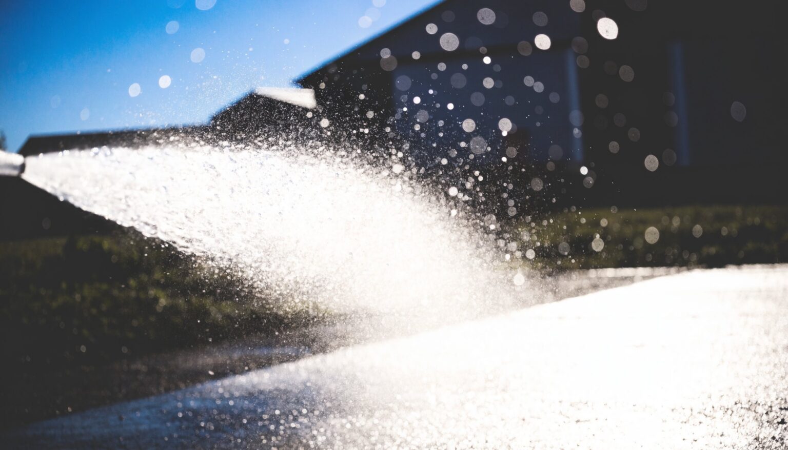 Kräftiger Wasserstrahl mit Sprühnebel beim Reinigen eines Hofbodens