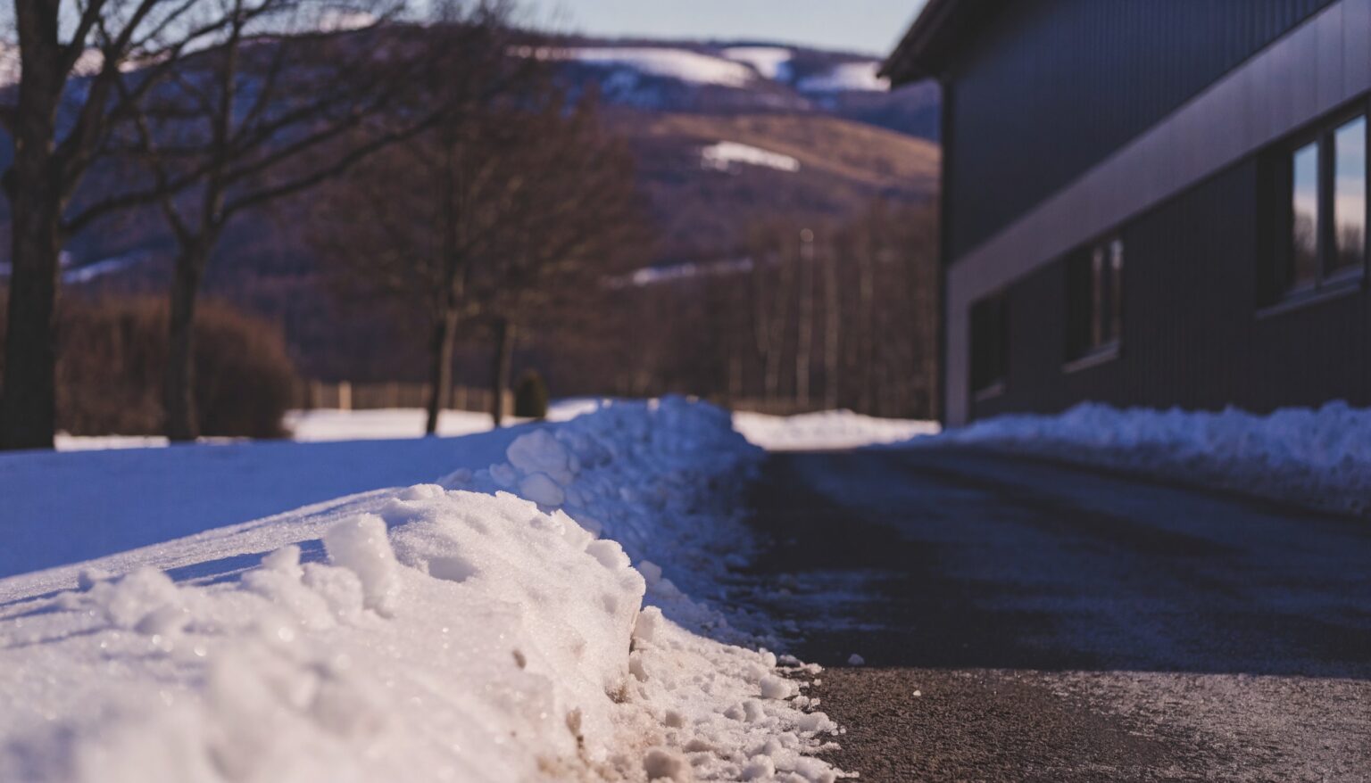 Freigeräumte Hofzufahrt mit Schneewall am Rand an einem Wintermorgen